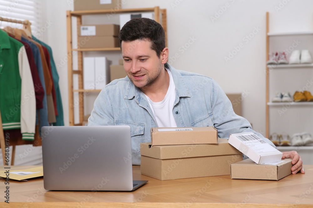Seller with parcels and laptop working in office. Online store Seller with parcels and laptop working in office. Online store