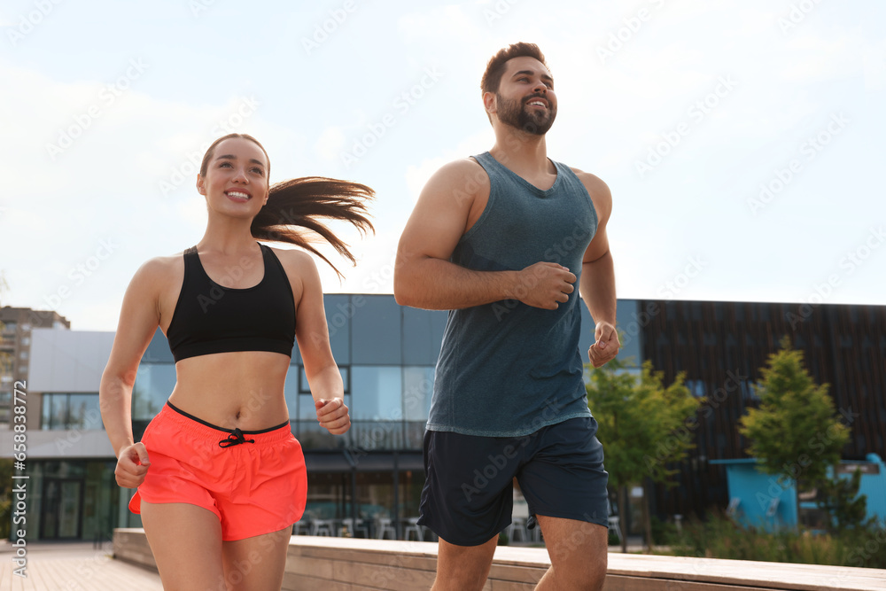 Healthy lifestyle. Happy couple running outdoors on sunny day, low angle view Healthy lifestyle. Happy couple running outdoors on sunny day, low angle view