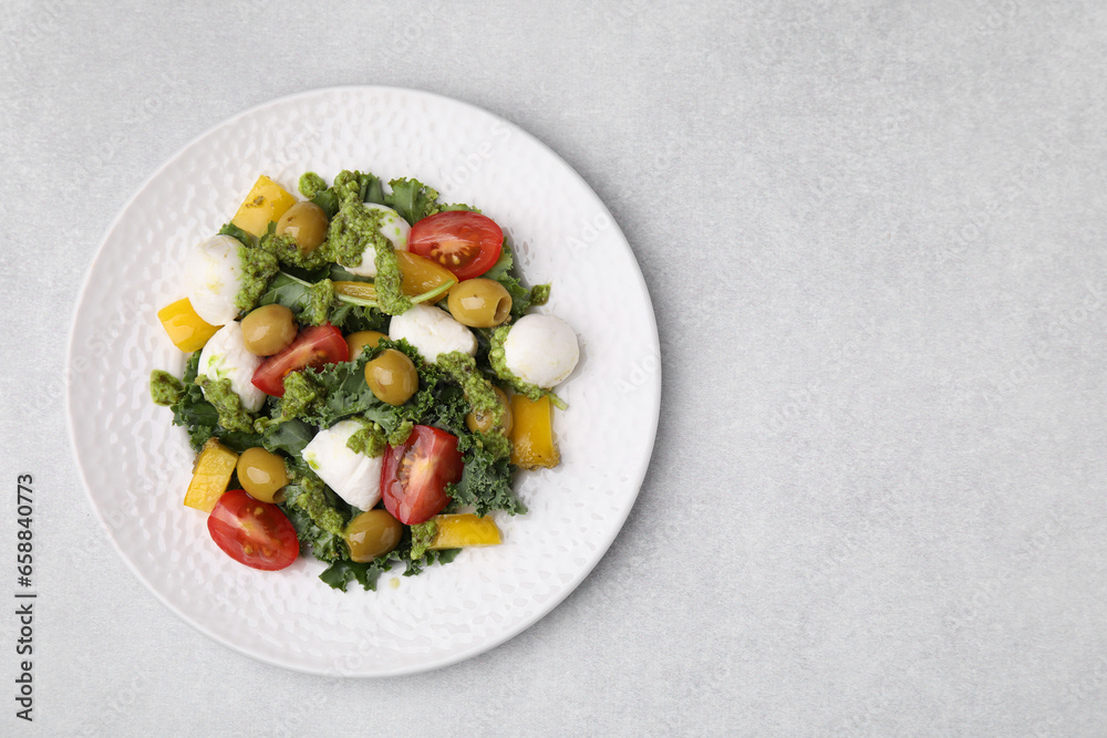 Delicious salad with pesto sauce on light table, top view. Space for text