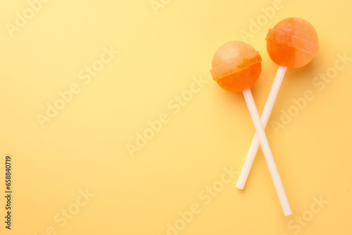 Tasty lollipops on yellow background, flat lay. Space for text