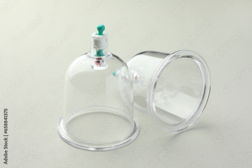Plastic cups on light grey background, closeup. Cupping therapy