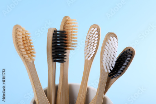 Bamboo toothbrushes in holder on light blue background  closeup