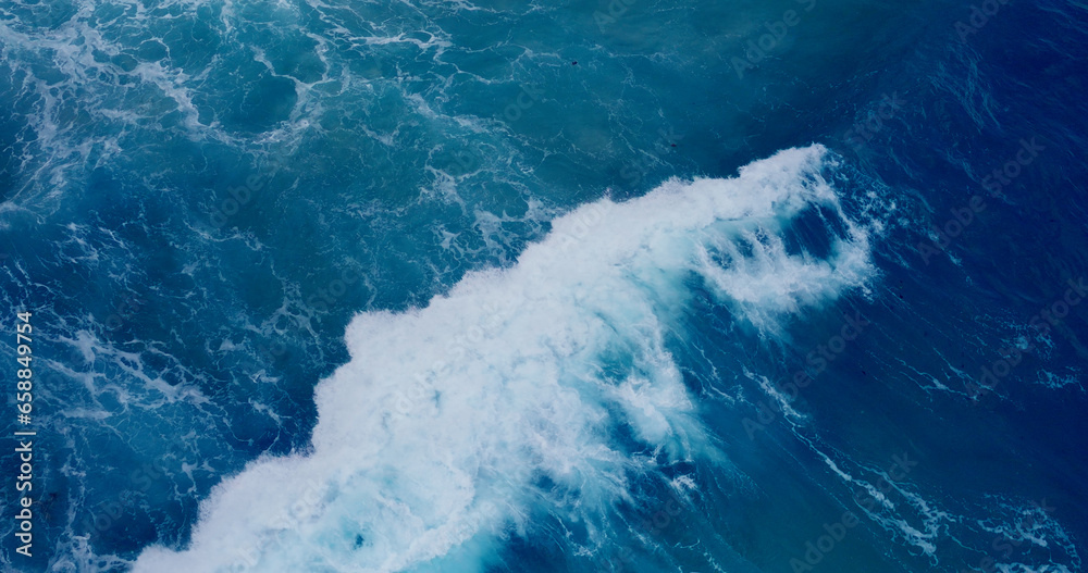 Slow motion sea wave Vitality of blue energy and clear ocean water. Powerful stormy sea waves in top-down drone shot perspective.  Crashing wave line in Andaman sea with foamy white texture.