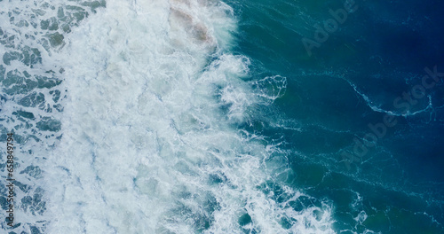 Slow motion sea wave Vitality of blue energy and clear ocean water. Powerful stormy sea waves in top-down drone shot perspective. Crashing wave line in Andaman sea with foamy white texture.