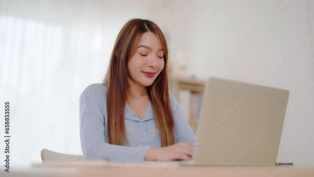 Young asian woman working at home. Happy female using computer laptop on desk at house Young asian woman working at home. Happy female using computer laptop on desk at house