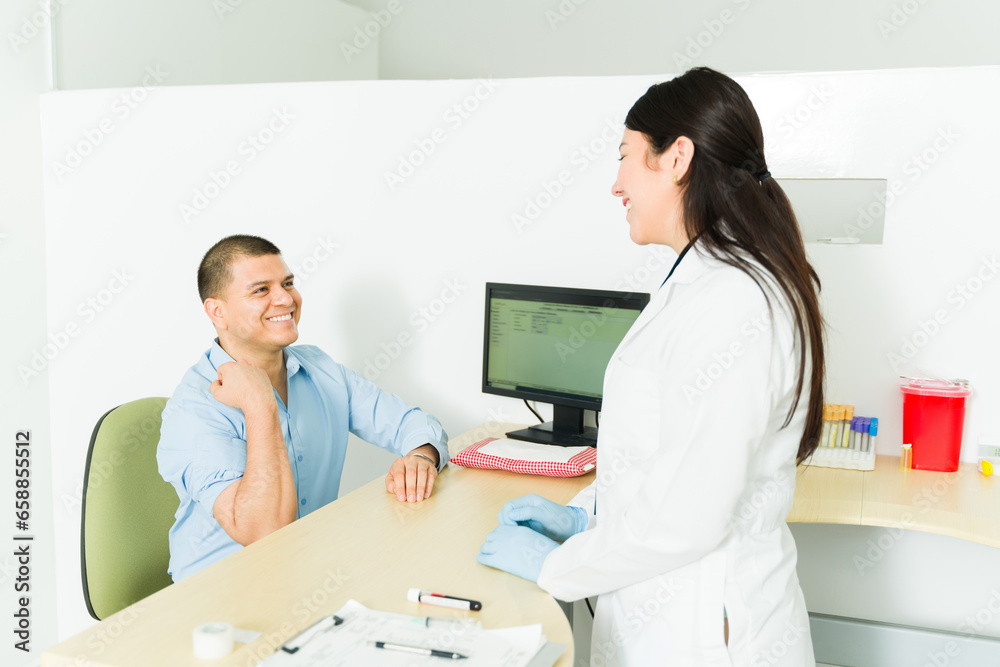 Fototapeta premium Smiling chemist taking a blood sample from a patient