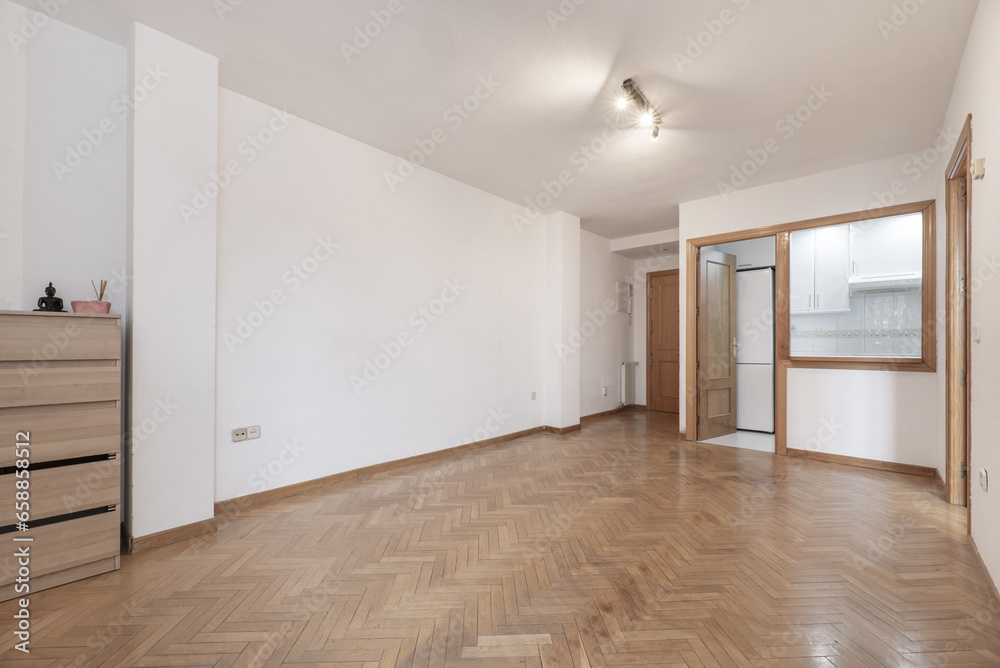 Living room of an empty house with parquet floors and a small kitchen with a serving hatch window Living room of an empty house with parquet floors and a small kitchen with a serving hatch window