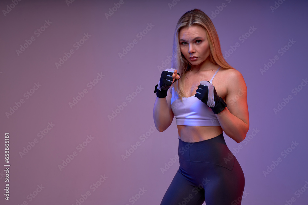 beautiful serious confident blonde female boxer looking at the camera, preparing to kick, close up portrait, isolated violet background, self-defense, strength training, motivation, copy space beautiful serious confident blonde female boxer looking at the camera, preparing to kick, close up portrait, isolated violet background, self-defense, strength training, motivation, copy space