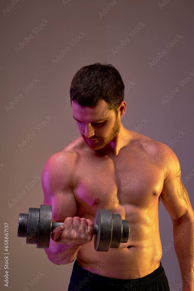 young motivated bodybuilder works out at studio, looking down,building the biceps and triceps