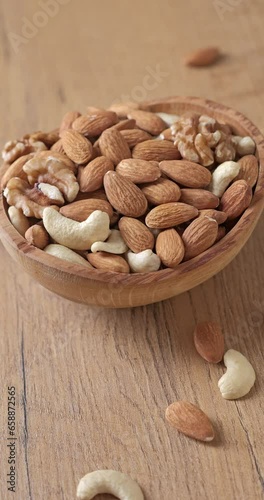 Assorted nuts of almonds, cashews, and walnuts in a wooden bowl. Healthy nutrition concept. Vertical video.
