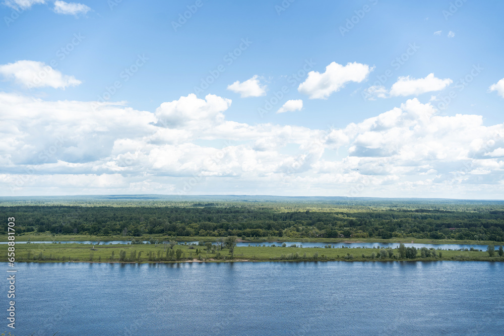 Landscape of a summer river. Cloudy sky, calm water, banks overgrown with forest. Free space for your text. High quality photo