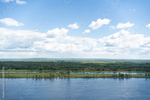 Landscape of a summer river. Cloudy sky  calm water  banks overgrown with forest. Free space for your text. High quality photo