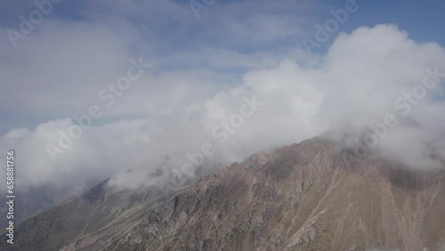 Flying above the mountain peak in the clouds