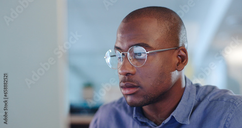 Serious black man, computer and focus for research, project deadline or trading at office. African male person, designer or employee working on PC or reading email, information or tasks at workplace