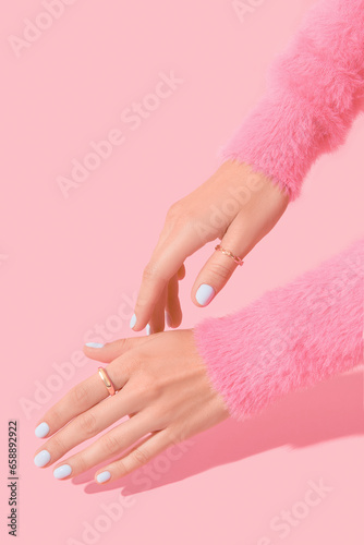 Womans hands with white manicure on pink background