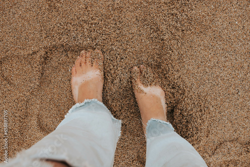 Woman with sandal tan lines toes in sand