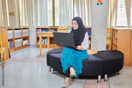 Asian muslim woman in hijab using laptop in office © Cavan