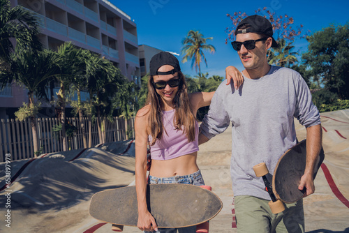 Young happy couple with skateboards enjoy longboarding at the skatepark photo