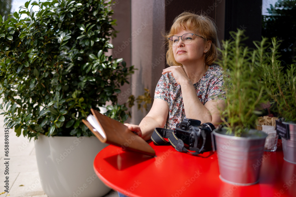 A female photographer sits at a red table in a street cafe. A female photographer sits at a red table in a street cafe.