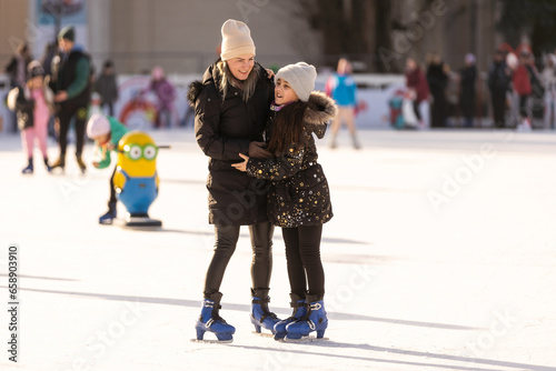 Mother with her daughters skates on ice skating
