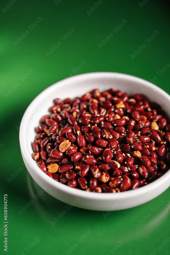 paintfu and red roasted peanuts in a white bowl on a green background. Chinese cuisine, hotpot ingredient paintfu and red roasted peanuts in a white bowl on a green background. Chinese cuisine, hotpot ingredient