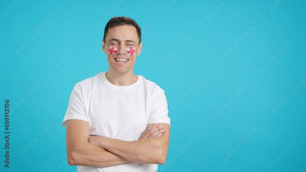Man standing with english flag painted on face smiling Man standing with english flag painted on face smiling