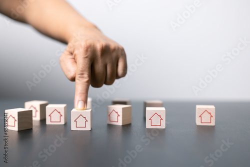 House and property investment and asset management concept. Interest rates, loan mortgage, house tax. Hand holding house icon on wooden block from stack with percent icon. Copy space for text.