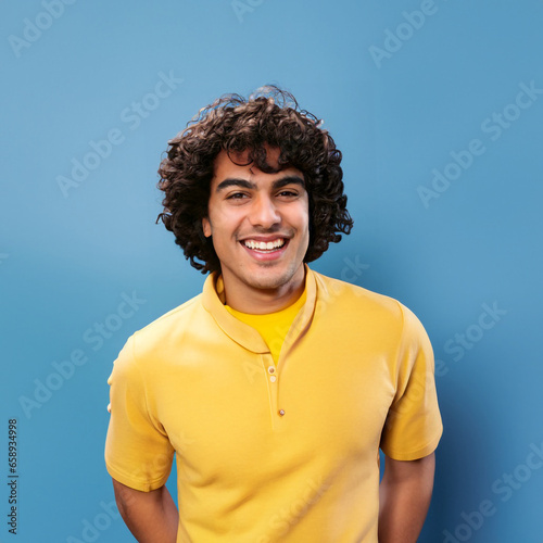 Curly hair man smiling and laughing, wearing a yellow t shirt on a bright solid blue background. created by generative AI technology