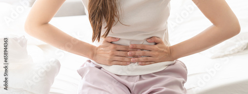 Flatulence ulcer, asian young woman, girl hands in belly, stomach pain from food poisoning, abdominal pain and digestive problem, gastritis or diarrhoea. Abdomen inflammation, menstrual period people. © KMPZZZ