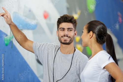 happy man and woman talking at indoor climbing gym wall