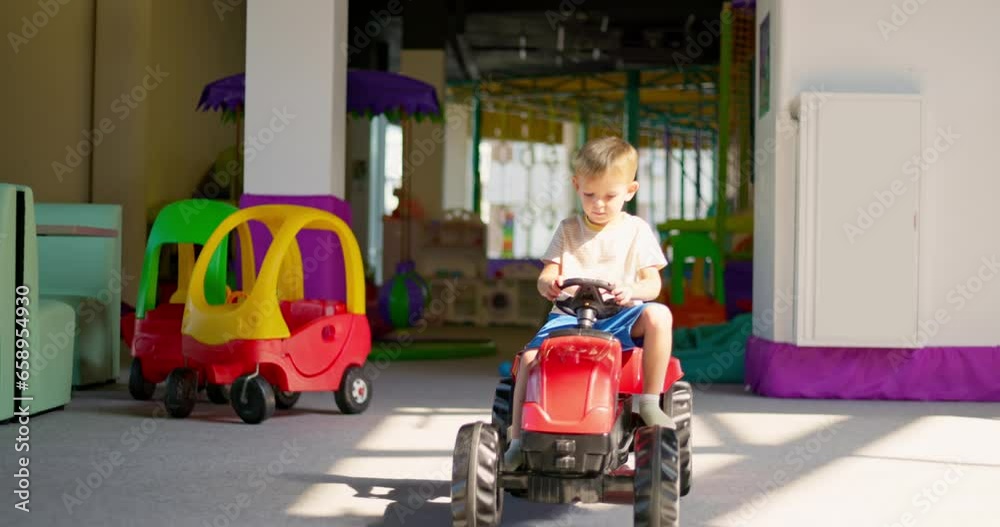 Boy driving a pedal car, child having fun riding a car in an amusement park Boy driving a pedal car, child having fun riding a car in an amusement park