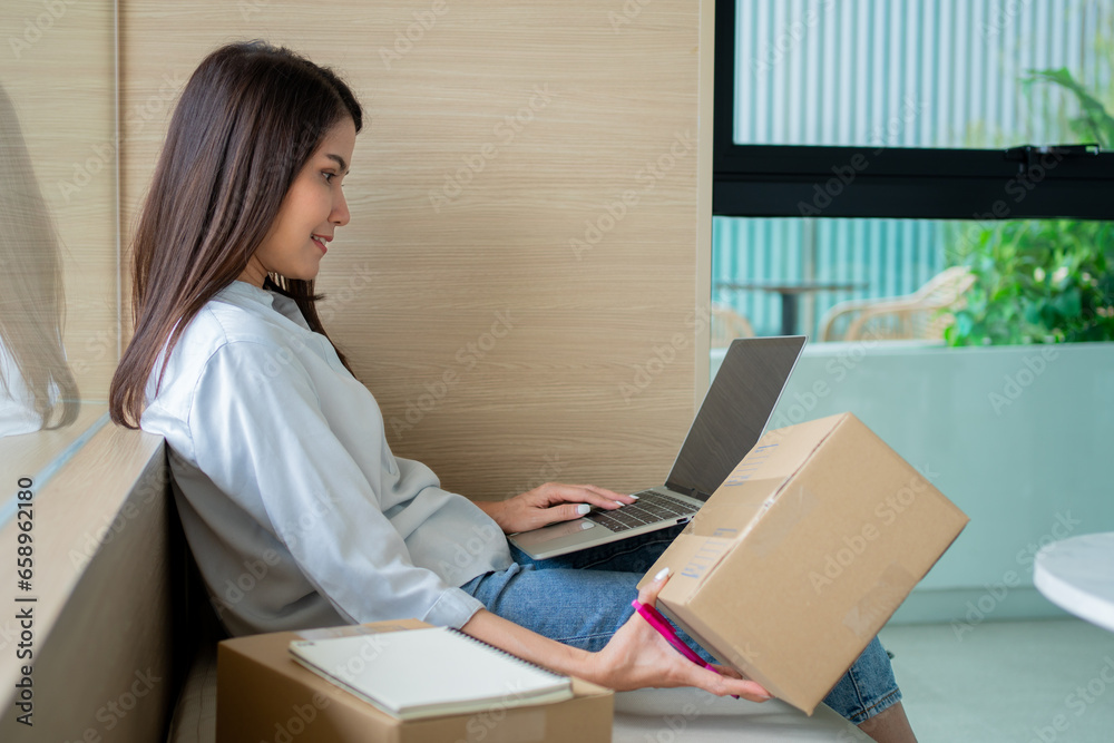 Happy young Asian woman entrepreneur, Smile for sales success after checking order from online shopping store in a laptop at home office, Concept of merchant business online and eCommerce Happy young Asian woman entrepreneur, Smile for sales success after checking order from online shopping store in a laptop at home office, Concept of merchant business online and eCommerce