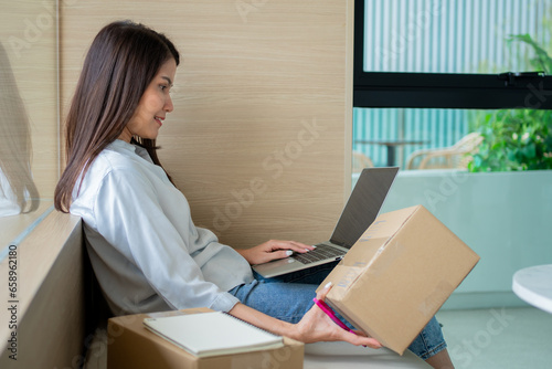 Happy young Asian woman entrepreneur, Smile for sales success after checking order from online shopping store in a laptop at home office, Concept of merchant business online and eCommerce