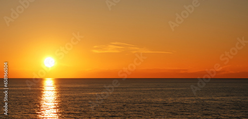 Beach seaside evening at sunset With rocks and hills orange sky © nana