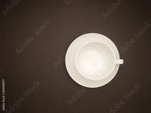 Top view of an empty white coffee cup on a black background.