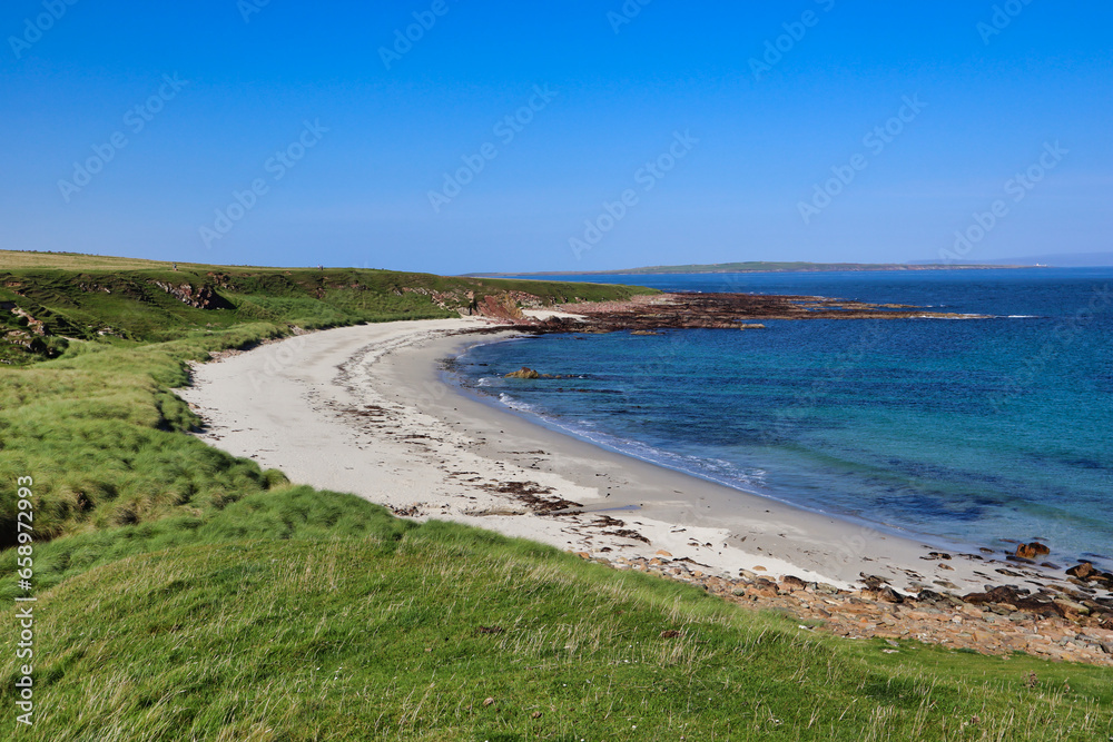 Blue water white sand scottish beach in scotland with grass and dunes