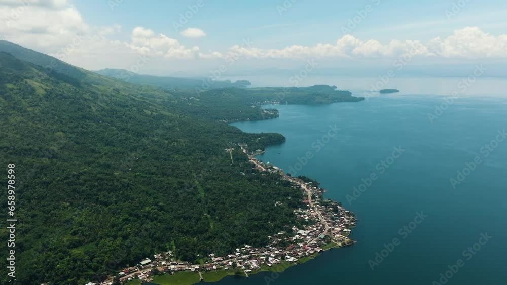 Aerial drone view of villages at lake coastline and mountain with jungle, forest, palm trees in Lanao del Sur. Mindanao, Philippines. Aerial drone view of villages at lake coastline and mountain with jungle, forest, palm trees in Lanao del Sur. Mindanao, Philippines.