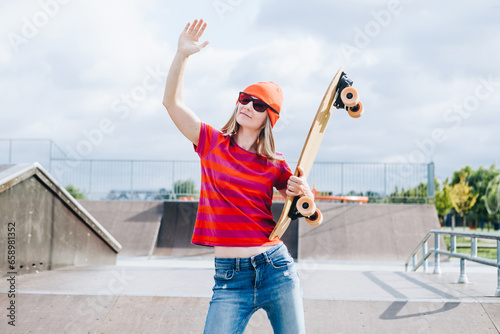 Portrait Of Skater Girl In Skatepark. Female In Casual Outfit have fun at scatepark on summer day. Active lifestyle, modern life, subculture concept photo