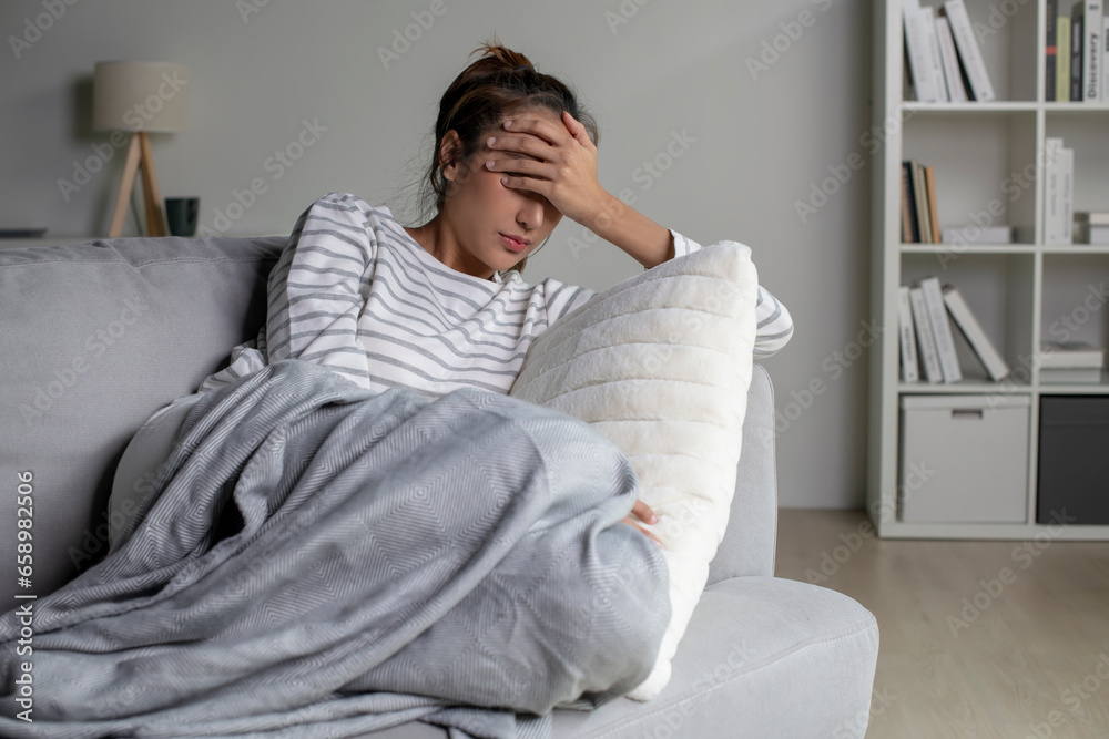 Lonely Asian woman in distress, worried, confused, lying on couch at home. Female suffer from mental health problems.