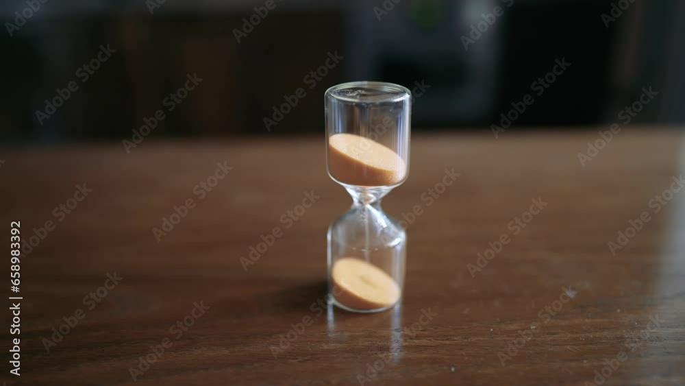 The timelapse pours sand in an hourglass. Time is running out fast. Stop time and start it back. A man's hand turns over an hourglass.