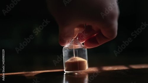 Timelapse sand pours in an hourglass in the rays of the sun. Time is running out fast. Stop time and start it back. A man's hand turns over an hourglass.
