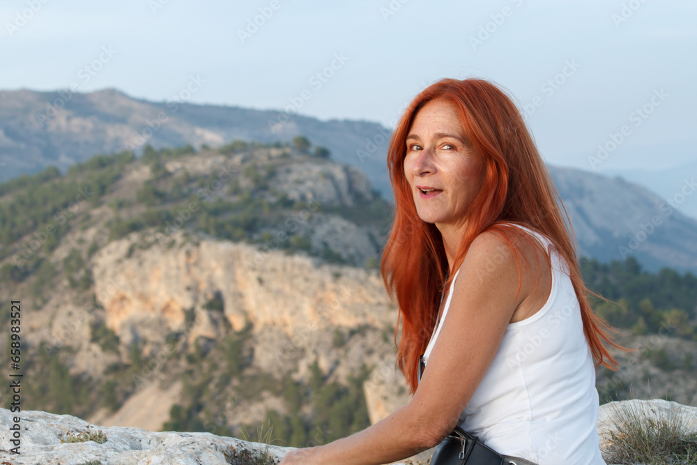 Mujer de mediana edad con el pelo rojo mirando a cámara en el Alt de les Pedreres de Alcoi, España