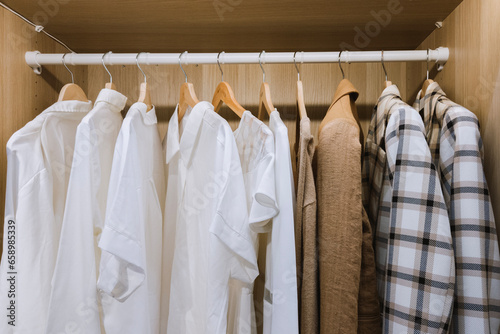 fashion clothing men shirt and female dress hanging on the wardrobe in the family dressing room at home.