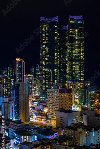 Busan City skyline, skyscrapers, and modern buildings at night, illuminated in vibrant colors over the Haeundae Beach in Kyongsang Namdo, South Korea