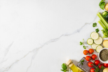 Top view healthy food cooking ingredients background with fresh vegetables, herbs, spices and olive oil on marble table with copy space