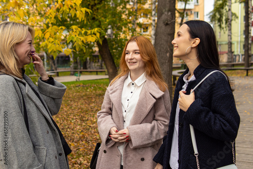 Three female friends chat in the park. Happy friends. Students or schoolgirls © Svetlana