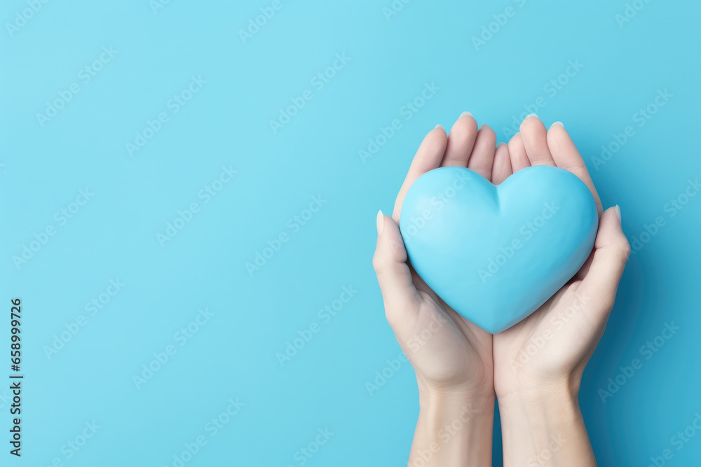 Female hands holding blue paper heart on blue background, top view with copy space Female hands holding blue paper heart on blue background, top view with copy space