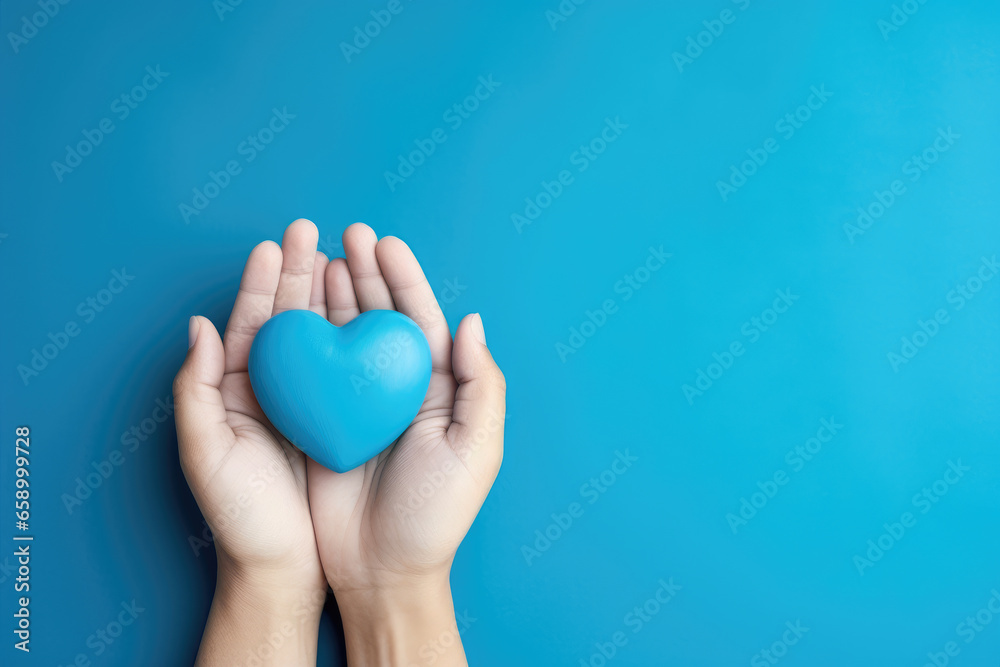 Female hands holding blue paper heart on blue background, top view with copy space Female hands holding blue paper heart on blue background, top view with copy space