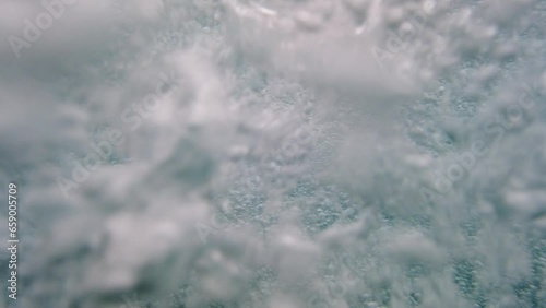 Close up, underwater, air bubbles from jacuzzi spa jet in swimming pool.