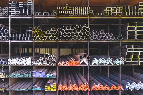 Group of various types of steel bars and pipes stacked on the storage shelf of building materials supply store